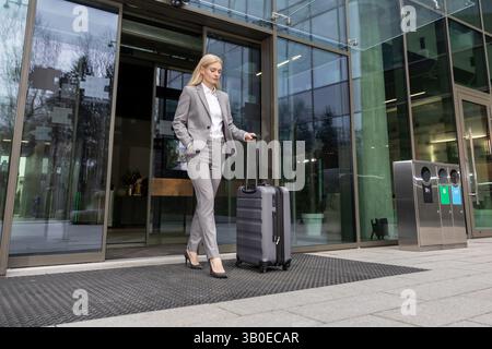 Woman entrepreneur carrying baggage while walking confidently from office Stock Photo