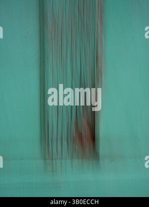 abstract blur background backdrop or wallpaper turquoise colored door with long narrow strips dripping downward blurred motion effect created with lon Stock Photo