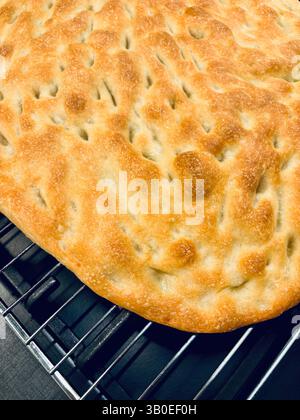 Freshly baked focaccia bread on dark background. Homemade traditional Italian food. Directly above. Stock Photo