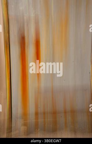 vertical abstract blur image of rust color orange and yellow rust dripping stripes on metal door concept created by long time exposure camera movement Stock Photo