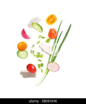Pieces of chicken meat and fresh vegetables falling on white background Stock Photo