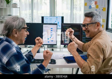 Senior developer team celebrates success in software collaboration and coding at a modern computer workstation Stock Photo