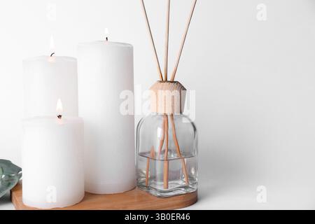 Burning candles with reed diffuser on white background Stock Photo