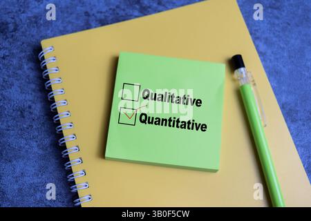 Concept of one person is answering question. he is choosing between qualitative and quantitative write on sticky notes isolated on Wooden Table. Stock Photo