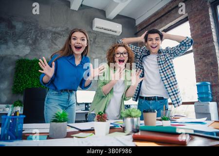 Energetic group of young colleagues celebrating success in a modern coworking space Stock Photo