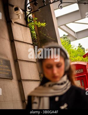 LONDON- APRIL 23, 2025: Candid street view of blurred pedestrian with CCTV camera in background Stock Photo