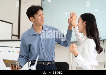 Team Collaboration and Success. Two professionals celebrating a successful project milestone with a high-five. Stock Photo