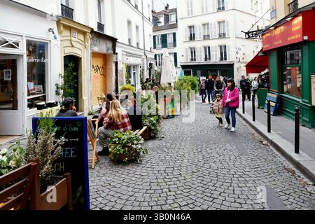 a charming, narrow cobblestone street scene in Paris, France, featuring traditional buildings with white facades, an art gallery ("Galerie d'art") Stock Photo
