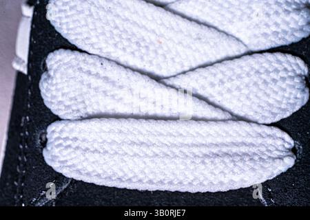 Lace-up on sneakers close-up. White, wide laces in black sneakers. High quality photo Stock Photo