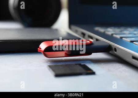 Flash drive connected to laptop, SD memory card and external hard disk on gray table, closeup Stock Photo