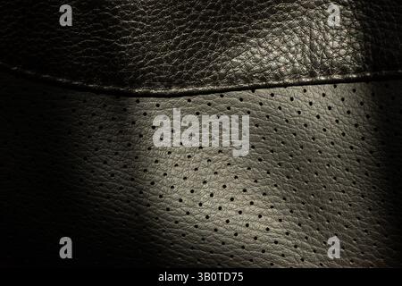Texture of black perforated leather with small holes and textured surface, background of black leather Stock Photo