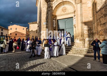 Numerous members of the Hermandad del Bautismo de Nuestro Señor Jesucristo gather in front of the Iglesia de San Pedro on Calle Trabuco in Cuenca, Castilla-La Mancha, Spain, in anticipation of the Procesión del Perdón (Procession of Forgiveness). The brotherhood is one of 33 hermandades that stage a total of eleven processions during Cuenca's Semana Santa. Stock Photo