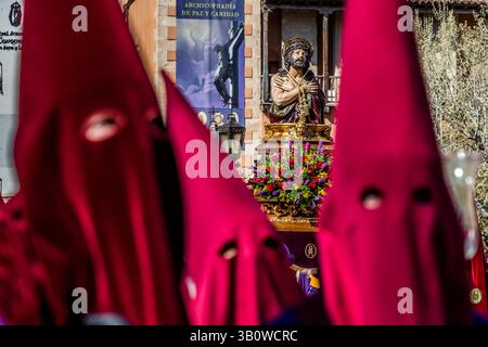 The paso 'Santísimo Cristo de las Misericordias', also known as the 'Cristillo de Paz y Caridad', is the emblem and main paso of the Archicofradía de Paz y Caridad and traditionally opens its procession on Maundy Thursday in Cuenca, Castilla-La Mancha, Spain. The figure shows Christ after the scourging, hands bound, wearing the crown of thorns, with an expression of meekness and suffering. A large garland of flowers decorates the paso, and crimson hoods of the penitents frame the scene. The Archicofradía de Paz y Caridad is one of 33 hermandades that stage a total of eleven processions during  Stock Photo