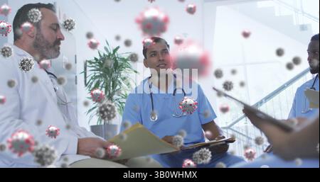 Diverse medical team reviewing files and discussing pandemic response in clinic with virus overlays Stock Photo