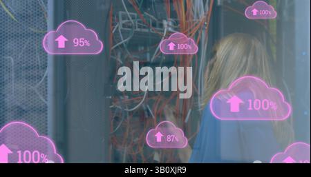 Image of cloud icons with growing numbers over caucasian woman in server room Stock Photo