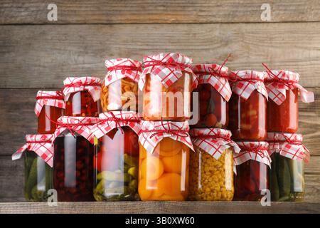 Many jars with different pickled products on wooden table Stock Photo