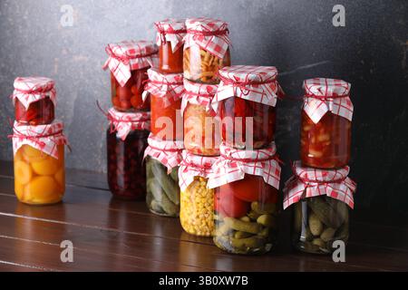 Many jars with different pickled products on wooden table Stock Photo