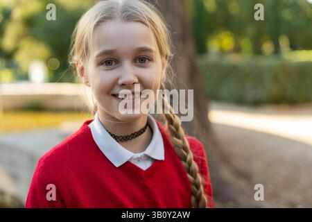 A cheerful girl with a long braid, dressed in bright red, joyfully enjoying a sunny day outside in nature Stock Photo