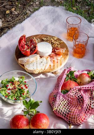 life view picnic scene featuring fresh pomegranates, walnuts, pine nuts, and creamy white cheese displayed on a wooden board, natural sunlight pomegra Stock Photo