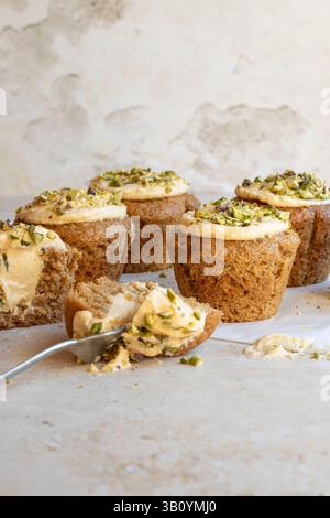 Spelt muffins with an orange cream cheese filling and topped with pistachios Stock Photo