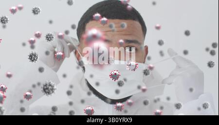 Adjusting man in protective suit and gloves fixing mask straps in studio, with virus particles Stock Photo