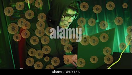 Image of bitcoins over asian male hacker in server room Stock Photo
