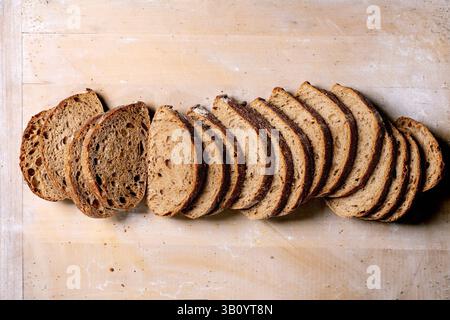 Freshly baked artisan sourdough bread sliced into portions on wooden background. Crusty rustic loaf with airy texture shows natural fermentation patte Stock Photo