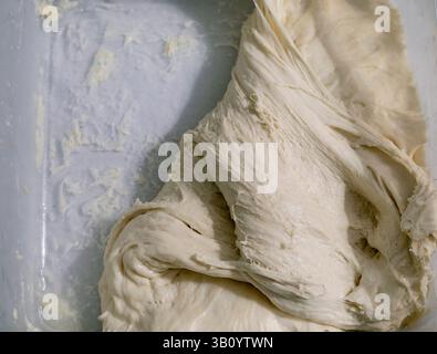 Fresh yeast dough close up. Homemade bread preparation process. Raw bread dough texture elastic structure of rising dough. Stock Photo