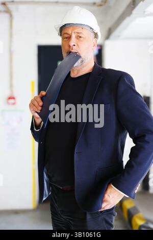 Mature male project manager holding clipboard, looking directly at camera. Stock Photo