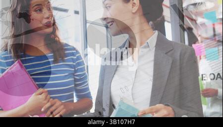 Statistical data processing against two caucasian businesswomen discussing at office Stock Photo