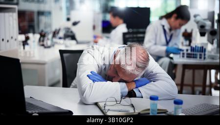 Tired, scientist and man sleeping in laboratory for burnout, deadline and exhausted with research. Medical science, fatigue and mature professional Stock Photo