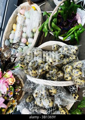 Decorative eggs, fresh flowers, and green plants arranged in rustic baskets Stock Photo