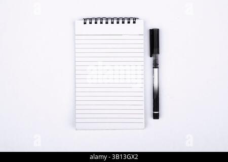 A minimalistic top-down view of an open blank notebook placed beside a black pen on a clean white background. Ideal for themes related to writing, jou Stock Photo