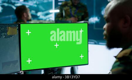 Army IT expert in control center collecting real time battlefield data, process satellite surveillance imagery for successful military defense mission. Using green screen isolated display. Camera A. Stock Photo