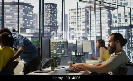 Person with impairment processing and analyzing data to automate decision making processes. IT specialist with disability programming in office, sitting in wheelchair, camera B Stock Photo