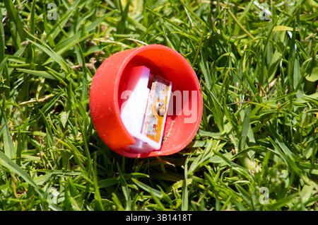 red circular pencil sharpener sitting in grass Stock Photo
