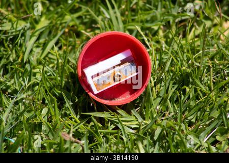red circular pencil sharpener sitting in grass Stock Photo