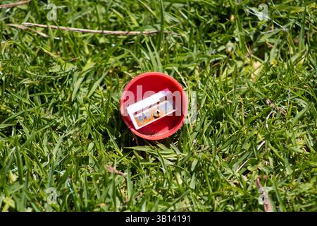 red circular pencil sharpener sitting in grass Stock Photo