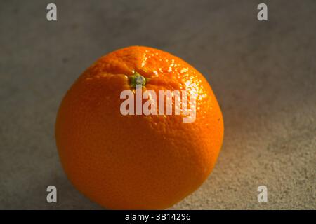 miniature orange sitting on pavement Stock Photo