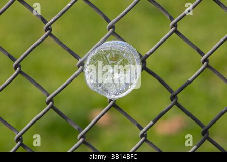 plastic water bottle stuck in chain link fence Stock Photo