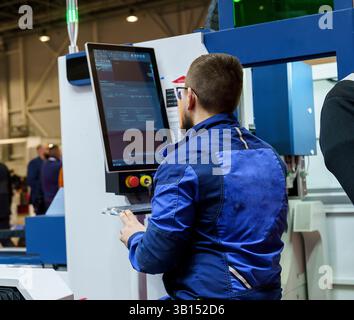 03/11/2025, Russia, novosibirsk,expocentre, welding exhibition,  a worker at the cnc machine controls the process of work and production of parts, ind Stock Photo
