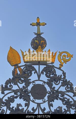 Golden cross with golden crown on metal gate with decorations, mitre, orb, crosier, handicraft, forging, metalwork, detail, cut-out, St. Mauritius Chu Stock Photo