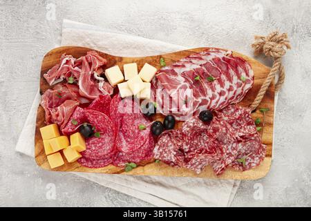 Assorted, sliced meat appetizer, prosciutto, salami and ham, with cheese and olives, on a wooden board, breakfast, top view, close-up, no people Stock Photo