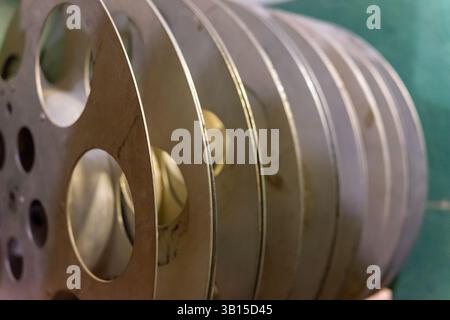 A collection of vintage film reels is carefully stacked on a green surface, showcasing their metallic sheen and unique design. These reels represent c Stock Photo
