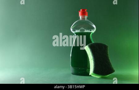 Basic tools for hand scrubbing with plastic bottle with green liquid product and scouring pad with abrasive and sponge surface isolated on green base Stock Photo