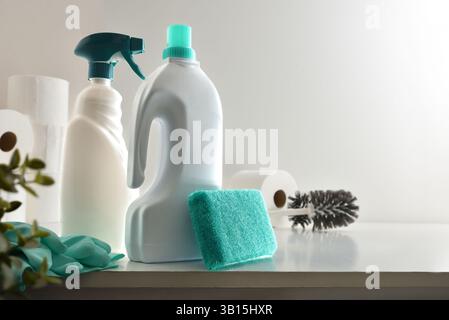 Bathroom cleaning supplies such as disinfectant bottles, scouring pads, gloves, toilet brush and toilet paper on white wooden table and  white isolate Stock Photo