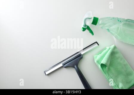 Window cleaner spatula, spray product and green microfibre cloth isolated on white table. Top view. Stock Photo
