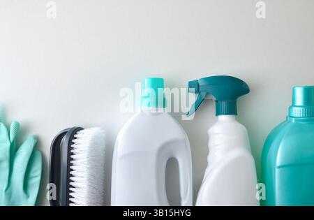 Detail of various cleaning products and supplies arranged in a line such as disinfectant chemicals, brush and gloves isolated on a white table. Top vi Stock Photo
