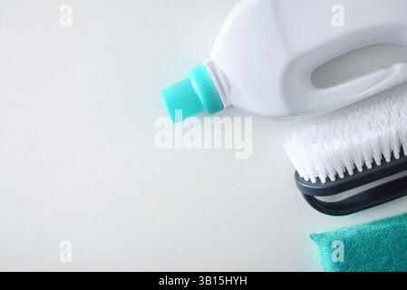 Detail of bottle with disinfectant products for cleaning gray brush with white bristles and green scouring pad isolated on white table. Top view. Stock Photo