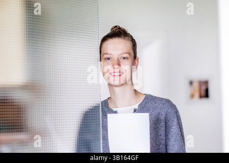 Young woman standing behind a glass door Stock Photo